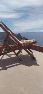 a wooden bench sitting on the side of the ocean at Inka Wasi in Isla de Sol