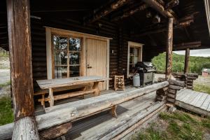 eine Blockhütte mit einem Picknicktisch und einem Grill auf der Veranda in der Unterkunft Villa Pikku Saana in Kilpisjärvi