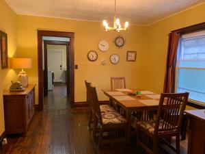 a dining room with a table and chairs and clocks on the wall at Red Brick Inn - Walk to the Falls, the Casino and all Downtown Restaurants in Niagara Falls +31 photos