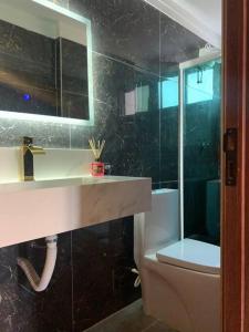 APARTAMENTO ENCANTADOR NA BEIRA-MAR DE MACEIÓ في ماسيو: حمام مع حوض ومرحاض ومرآة