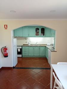 a kitchen with green cabinets and a white refrigerator at Casa do Poço in Quinta do Anjo