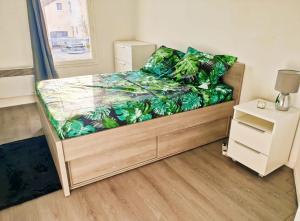 a small bedroom with a bed with a green leaf pattern at CHARMANT APPARTEMENT SUR SOTTEVILLES LES ROUEN in Saint-Sever