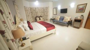 a bedroom with a bed and a couch and a television at Four Squares Karachi in Karachi