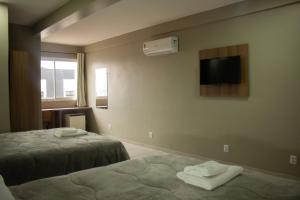 a hotel room with two beds and a flat screen tv at Hotel Executivo in São Borja