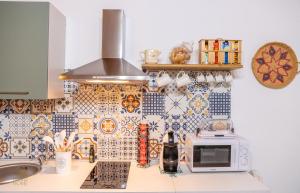 a kitchen with a counter with a microwave and tiles at Family Home in Quartu SantʼElena