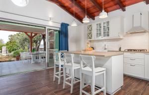 a kitchen with white cabinets and white bar stools at Vila s jacuzzijem i bazenom Mavrinac in Nerezine