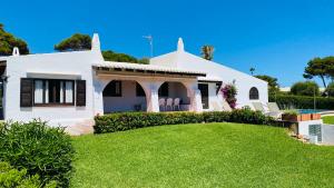 une maison blanche avec une pelouse devant elle dans l'établissement Villa Bini Kim, à Binibeca