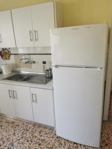 einen weißen Kühlschrank in einer Küche mit Spüle in der Unterkunft Evangelias House! in Stavros