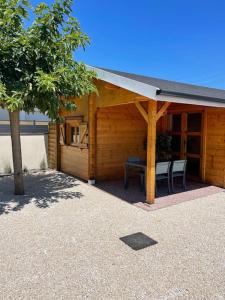 een houten hut met een tafel en stoelen erin bij Magnifique chalet aux portes de la Drôme in Saint-Rambert-dʼAlbon