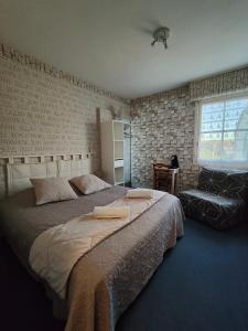 a bedroom with a large bed and a chair at Auberge Le Chata in Saint-Georges-de-Didonne