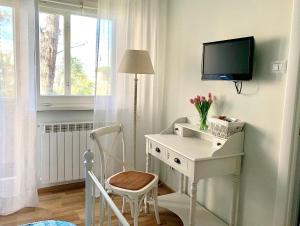 einen weißen Schreibtisch mit einem TV und einem Stuhl in einem Zimmer in der Unterkunft B&B EurGardenie in Rom