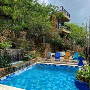 a swimming pool in front of a house with a fountain at Akela Gaira Hotel in Santa Marta