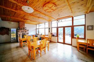 un restaurante con mesas y sillas de madera y ventanas en Alpenhaus Kazbegi Hotel & Restaurant, en Kazbegi