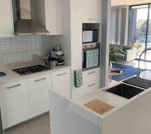 a kitchen with white cabinets and a stove top oven at Luxury 3 bdm Spacious apt in the heart of Wagga in Wagga Wagga