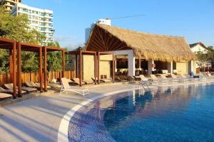 a swimming pool with lounge chairs and a straw hut at Apto Samaria Club de Playa, encanto del mar in Santa Marta