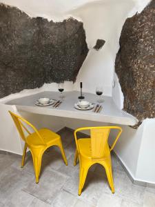 a table with two yellow chairs and a table with glasses at Casa Legko in Plaka Milou