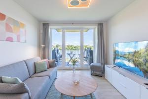 sala de estar con sofá, TV y mesa en Ferienwohnung "Die Komfortzone" direkt am Nordseedeich mit Blick auf den See, en Nordstrand