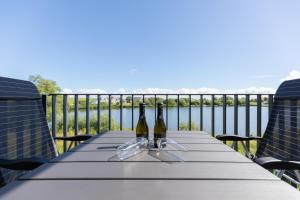 2 botellas de vino sentadas en una mesa en un balcón en Ferienwohnung "Die Komfortzone" direkt am Nordseedeich mit Blick auf den See, en Nordstrand