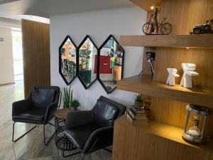 een salon met twee zwarte stoelen en een spiegel bij Hotel Caiçara in Cachoeiro de Itapemirim