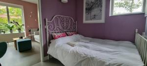 - une chambre avec un grand lit et un mur pourpre dans l'établissement Lovely 1 bedroom apartment with garden, à Amsterdam