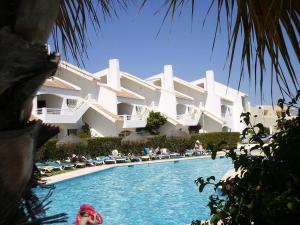 a man sitting in a pool in front of a building at Vila Nova- by Portugalferias in Carvoeiro