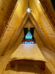 - un lit dans un grenier en bois avec une fenêtre dans l'établissement Rajska suma, à Žabljak