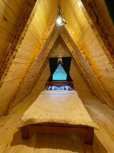 a bed in a wooden attic with a window at Rajska suma in Žabljak