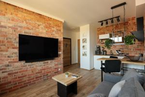 a living room with a brick wall with a flat screen tv at Nobel 55 Apartament in Władysławowo