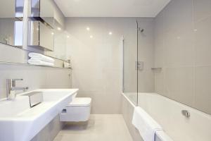 a white bath tub sitting next to a white sink at Templeton Place by Supercity Aparthotels in London