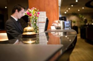 Fletcher Hotel-Restaurant Weert في فيرت: رجل في بدلة يجلس على طاولة مع إناء من الزهور