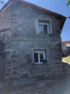 una casa in pietra con due finestre sul lato di Casa Pedragude. Turismo rural. a Pantón