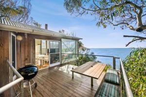a house with a deck with a bench and the ocean at Hideaway At Wye in Wye River