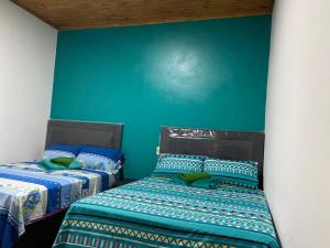2 camas en una habitación con una pared verde en Hospedaje La Perla, en Encarnación