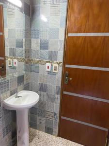 a bathroom with a sink and a wooden door at Hospedaje La Perla in Encarnación