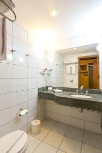 a bathroom with a toilet, sink, and mirror at Hotel Exclusivo in São José dos Pinhais
