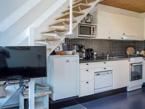 uma cozinha com armários brancos e uma televisão em Holiday home Vestervig XXXVIII em Vestervig