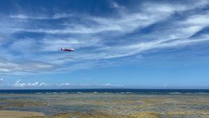 a plane flying in the sky over the ocean at ゴールデンマイルヴィラ in Amami