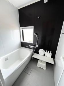 a white bathroom with a tub and a toilet at ゴールデンマイルヴィラ in Amami