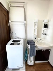 a small bathroom with a sink and a white refrigerator at ゴールデンマイルヴィラ in Amami
