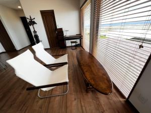 a living room with a wooden table and white chairs at ゴールデンマイルヴィラ in Amami