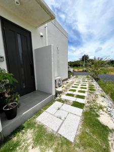 a house with a black door and a walkway at ゴールデンマイルヴィラ in Amami