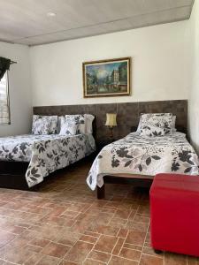 a bedroom with two beds and a painting on the wall at Cabaña Campestre Miraluna in Choachí