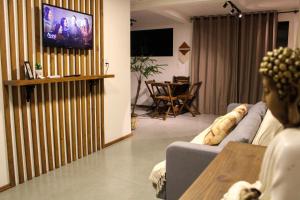 a person sitting on a couch watching a tv in a living room at Pousada Refúgio do Vale - Praia do Rosa in Praia do Rosa