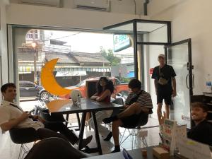 a group of people sitting around a table in a room at Prachan Hostel in Thong Sala