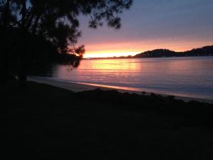 a sunset over a body of water at Currawong Beach Cottages in Great Mackerel Beach
