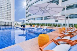 a pool with chairs and umbrellas next to a building at FLAT Pelinca América in Campos dos Goytacazes