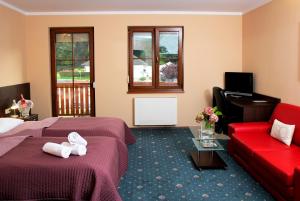 a hotel room with two beds and a red couch at Sportpenzion Pohoda in Pilsen