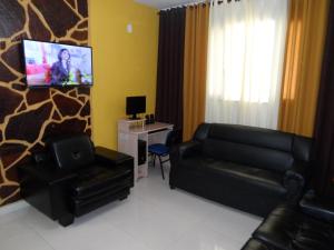 uma sala de estar com mobiliário de couro preto e uma televisão de ecrã plano em Hotel Avenida em Vitória