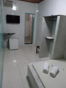 a bathroom with a tub and a tv in a room at Hotel Avenida in Vitória