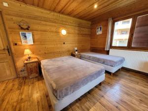a bedroom with two beds in a wooden cabin at Appartement cosy aux Gets, idéal pour la famille, proche pistes et commerces - FR-1-598-104 in Les Gets